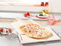 Pizza auf einem Pizzastein mit einem Holzspatel.