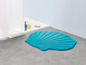 Eine blaue Badematte in Muschelform im Badezimmer.