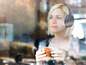 Eine Frau mit Philips Kopfhörern trinkt Kaffee.