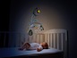 Ein Baby liegt in einem Kinderbett mit einem Chicco-Mobile darüber.