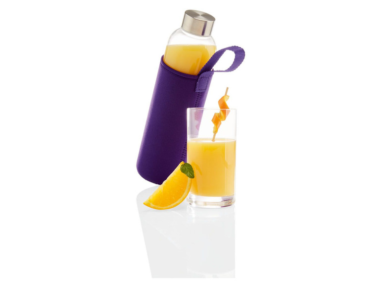 Eine Glasflasche mit Saft, ein Glas Saft und eine Orangenscheibe.