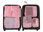 Ein rosafarbenes Set mit Aufbewahrungstaschen für Kleidung, Schuhe und Toilettenartikel in einem Koffer.