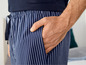 Ein Mann trägt eine dunkelblaue Pyjamahose mit weißen Streifen.