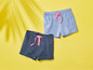 Zwei Paar Shorts für Mädchen, eine mit blauen Streifen und eine einfarbig blau.