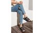 Frau in blauen Jeans trägt schwarze Sandalen mit zwei Riemen.