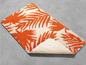 Eine orangefarbene Badematte mit Palmenblatt-Muster.