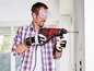 Ein Mann bohrt mit einem Einhell Bohrhammer ein Loch in eine Wand.