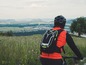 Ein Mountainbiker mit Rucksack blickt über eine hügelige Landschaft.