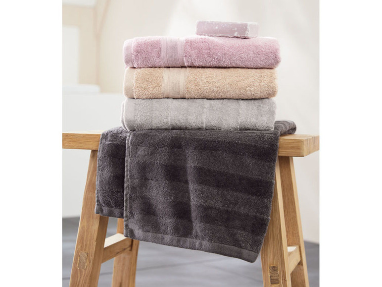 Ein Stapel Handtücher in verschiedenen Farben, darunter grau, beige, rosa und dunkelgrau.