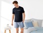 Mann in schwarzem T-Shirt mit dem Schriftzug 'RESTART WEEKEND' und blauen Shorts