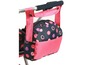 Eine rosa und schwarze Tasche mit Punkten, die an einem Kinderwagen befestigt ist.
