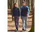 Ein Mann und eine Frau gehen im Wald in Sportbekleidung spazieren.