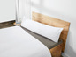 Ein weißes Kissen auf einem Bett mit einem Holz-Kopfteil.
