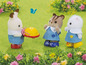 Drei Calico Critters Puppen in blauen Kleidern spielen draußen.