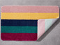 Eine Badematte mit Streifen in Rosa, Gelb, Dunkelblau, Grün und Rot.