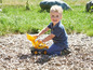 Ein Junge spielt mit einem gelben Spielzeugbagger auf einem Spielplatz.