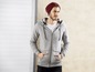Ein Mann trägt einen grauen Hoodie mit Kapuze und eine rote Mütze.