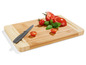 Ein Bambus-Schneidebrett mit Tomaten, Basilikum und einem Messer.