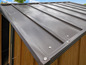 Ein graues Metalldach eines Schuppen mit Holzwänden.