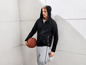 Mann in einem schwarzen Hoodie und grauen Jogginghose mit einem Basketball.