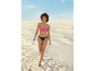 Eine Frau in einem rosafarbenen Bikini geht am Strand entlang.