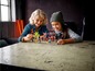 Zwei Kinder spielen mit LEGO® NINJAGO® Minifiguren und Zubehör.