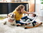 Eine Frau mit einem Baby in einem K's Kids Schaukelstuhl und einem Hund.