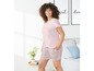 Eine Frau trägt einen rosafarbenen Pyjama mit kurzen Hosen mit Blumenmuster.