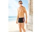 Mann mit schwarzer Badehose mit orange-schwarzem Muster am Strand