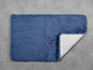 Eine blaue Badezimmermatte mit rutschfestem Untergrund.