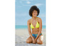 Eine Frau in einem gelben Bikini sitzt am Strand.