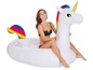Eine Frau schwimmt auf einem aufblasbaren Einhorn mit Regenbogen-Schwanz.