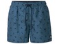 Blaue Badehose mit Palmenprint und 'Tropical Vibes' Logo.