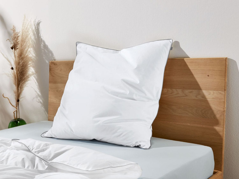 Ein weißes Kissen auf einem Bett mit einem Holzkopfteil.