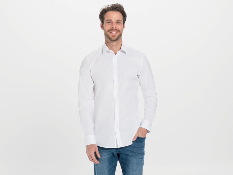 Mann in einem weißen Hemd und blauen Jeans.