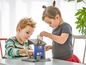 Zwei Kinder spielen mit einer blauen Garage und einem Auto.
