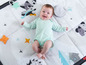 Baby auf einer Tiny Love Spielmatte mit Tieren und Sternen.