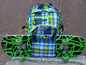 Ein Skateboard mit grünen Rollen und ein grün-blauer karierter Rucksack.