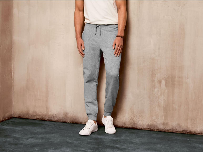 Mann in grauen Jogginghosen und weißen Sneakern.