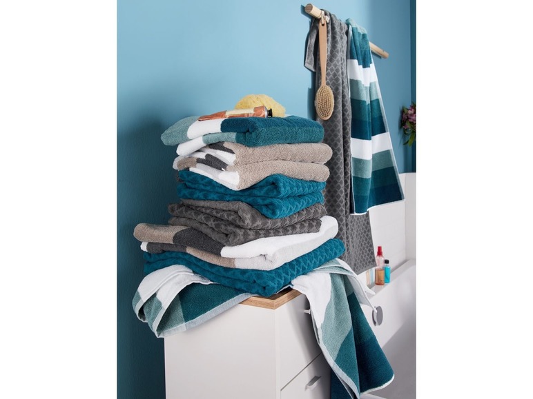 Stapel Handtücher in verschiedenen Farben und Mustern in einem Badezimmer.