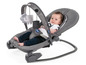 Ein Baby in einem Chicco-Schaukelsitz mit einem Spielbogen.