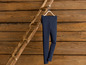 Dunkelblaue Leggings, die an einer Holzleiter gegen eine Holzwand hängen.