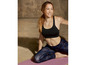 Frau in Sport-BH und Tarnleggings auf einer Yogamatte.