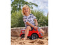 Ein Junge spielt mit einem roten Spielzeug-LKW im Sand.