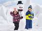 Zwei Kinder in Winterkleidung spielen im Schnee mit einem Schneemann.