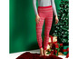 Frau trägt rote Weihnachtsleggings mit Weihnachtsbaum und Geschenken im Hintergrund.