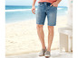Mann in blauen Jeanshorts und grauen Espadrilles am Strand.