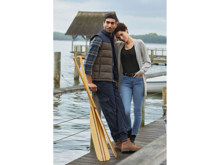 Ein Mann und eine Frau stehen auf einem Holzsteg mit zwei Holzpaddeln.