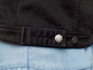 Eine schwarze Jeansjacke mit silbernen Knöpfen und einem Denim-Detail.