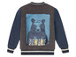 Eine graue und blaue Bomberjacke mit einem Bärenprint und dem Text 'BEWARE'.